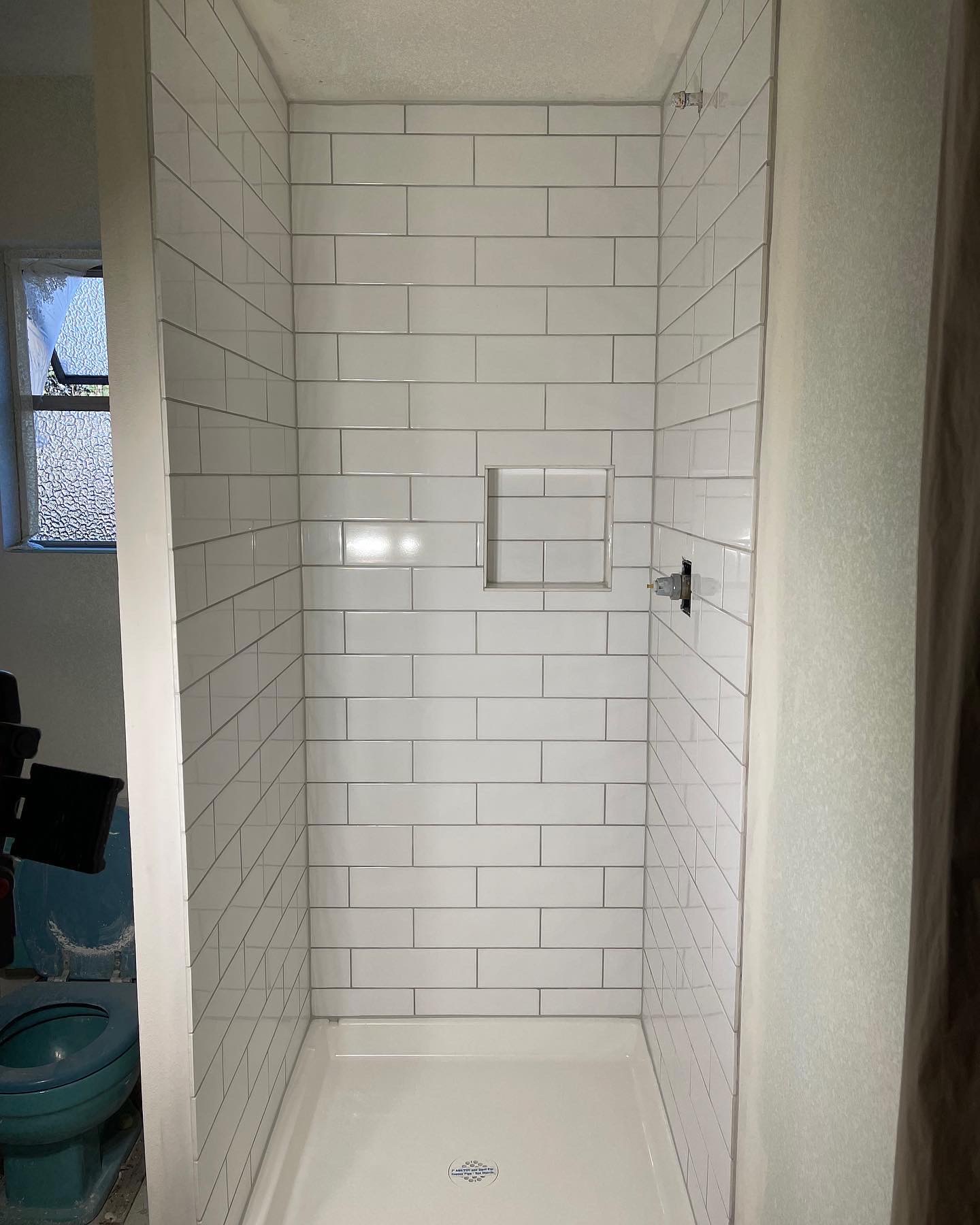 Bathroom shower after professional remodel - modern tiles with pristine white grout transformation